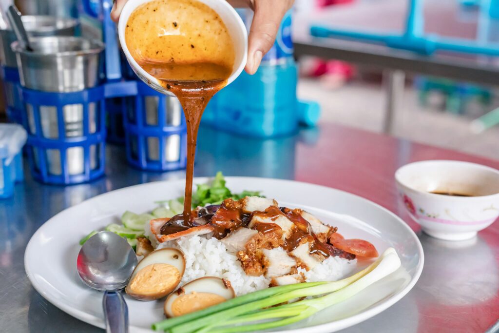 Khao Moo Daeng – Thai BBQ Pork with Rice Close-up of Thai Khao Moo Daeng with sauce poured over rice and pork