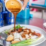 Close-up of Thai Khao Moo Daeng with sauce poured over rice and pork