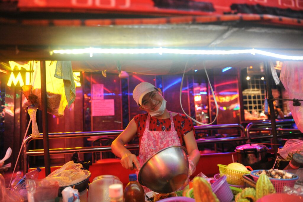 Night Food Vendor in Bangkok’s Chinatown Smiling street food vendor cooking at night in Yaowarat Bangkok