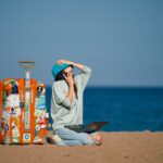 Woman with a laptop and suitcase on a tropical beach, ready to start her digital nomad journey in Southeast Asia